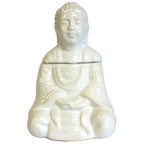 Complete white ceramic oil burner in the form of a seated Buddha with a detachable head. The Buddha is depicted with serene facial features, textured hair, and detailed robe folds, finished in a glossy glaze.