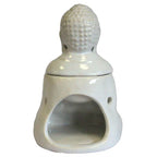 White ceramic oil burner shaped like a Buddha figure, photographed from the back. The removable Buddha head sits on top, with a hollow opening below for placing a tealight candle. The glossy finish reflects light on the surface.