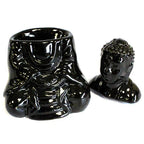 Glossy black ceramic Buddha-shaped oil burner shown in two parts: the body with a detailed robe design and hollow cavity for placing a tealight, and the detachable Buddha head placed on the side. The body reveals the seated Buddha’s crossed legs and draped robe details.