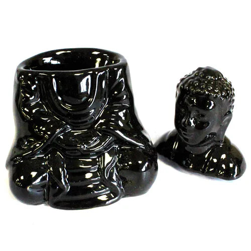 Glossy black ceramic Buddha-shaped oil burner shown in two parts: the body with a detailed robe design and hollow cavity for placing a tealight, and the detachable Buddha head placed on the side. The body reveals the seated Buddha’s crossed legs and draped robe details.