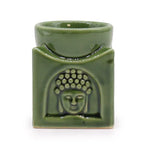 Green ceramic oil burner with square design, featuring a detailed Buddha face carved on the front. The burner has a circular dish at the top for essential oils or wax melts, and a hollow section below for placing a tealight candle, making it ideal for aromatherapy use.