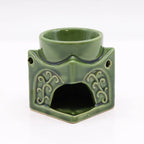 Rear view of a green ceramic Buddha oil burner with hexagonal base, intricate floral patterns, and a round top dish for oils or wax melts. The open cavity at the bottom is meant for placing a tealight candle, making it a decorative and functional aromatherapy accessory.