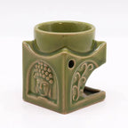Side view of a green ceramic Buddha oil burner with detailed embossed patterns, featuring a serene Buddha face and decorative swirls, designed for aromatherapy and home fragrance.