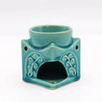 Rear view of a turquoise ceramic Buddha oil burner with decorative vine patterns and a large opening to place a tealight candle.