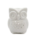 A charming, white ceramic owl oil burner and wax warmer with a shiny finish. The owl features large, textured circular eyes and small, round cutouts on its body, allowing light from a candle to shine through. The top of the owl's head is shaped into a small bowl for diffusing essential oils. 