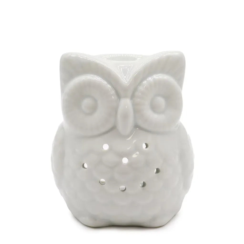 A charming, white ceramic owl oil burner and wax warmer with a shiny finish. The owl features large, textured circular eyes and small, round cutouts on its body, allowing light from a candle to shine through. The top of the owl's head is shaped into a small bowl for diffusing essential oils. 