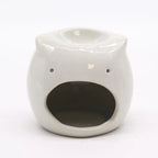A white, glossy ceramic owl essential oil burner on a white background. The spherical owl has an open circular back for a candle, with a lit orange wax tea light inside. The top of the owl's head features a shallow dish for essential oils or wax melts.