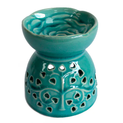 A striking, teal-colored ceramic oil burner with a glossy, crackle glaze finish. The top bowl features a detailed, raised rose pattern, while the base has a cutout tree of life design with heart-shaped leaves. This beautiful and unique home fragrance diffuser is ideal for aromatherapy, meditation, or as a decorative piece. The product is photographed against a clean white background, highlighting its vibrant color and intricate design.