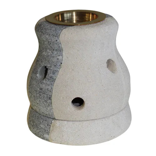 A stylish, dual-toned soapstone essential oil burner with a smooth, curved, hourglass-like shape. The burner is made from a combination of light cream-colored and dark gray, mottled soapstone, divided vertically down the center. The top has a  brass bowl for essential oils or wax melts. The base has small, rounded holes for ventilation. This unique and elegant piece of home decor is perfect for aromatherapy and is photographed against a clean white background.