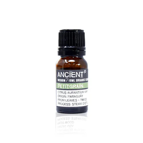 A small, 10ml amber glass bottle of Ancient Wisdom Organic Petitgrain essential oil. The bottle has a black cap and a black label with a light green band. The label lists product details including the Latin name, origin, and distillation process. The bottle is photographed against a clean white background.