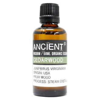 Amber glass bottle labeled 'Ancient Wisdom Organic Essential Oil Cedarwood 50ml,' origin USA, made from wood, steam distilled.