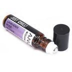 Amber glass roll-on bottle labeled "Just Chill!" by Ancient Wisdom. The purple label lists lavender, rose, and vetiver essential oils. Cap is removed and placed next to the roller applicator.