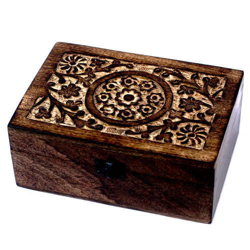 rectangular wooden box with a dark brown finish. The lid is adorned with intricate carved floral patterns, including a central circular medallion surrounded by flowers and leaves. The box has a small black metal clasp on the front and is photographed on a clean white background.