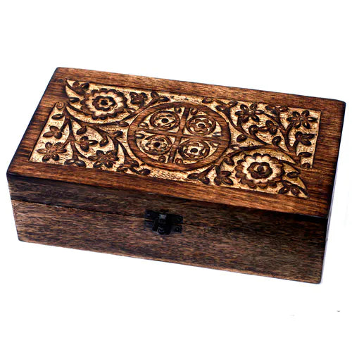 rectangular wooden box with a dark finish. The lid features a unique carved pattern with a central circular medallion divided into four sections, each containing a small flower, surrounded by a larger intricate floral and leafy design. The box has a small black metal clasp and is photographed on a clean white background.